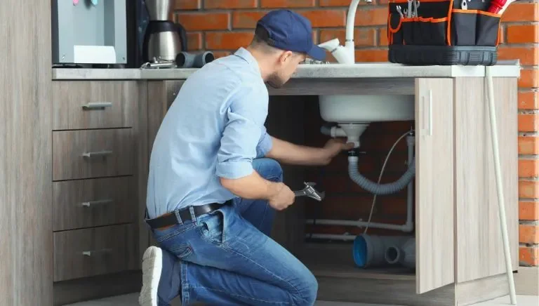 Plumber installing new plumbing under a kitchen sink