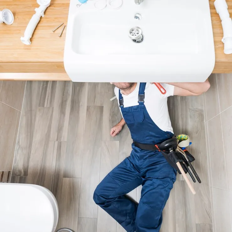 Plumber installing plumbing under a bathroom sink