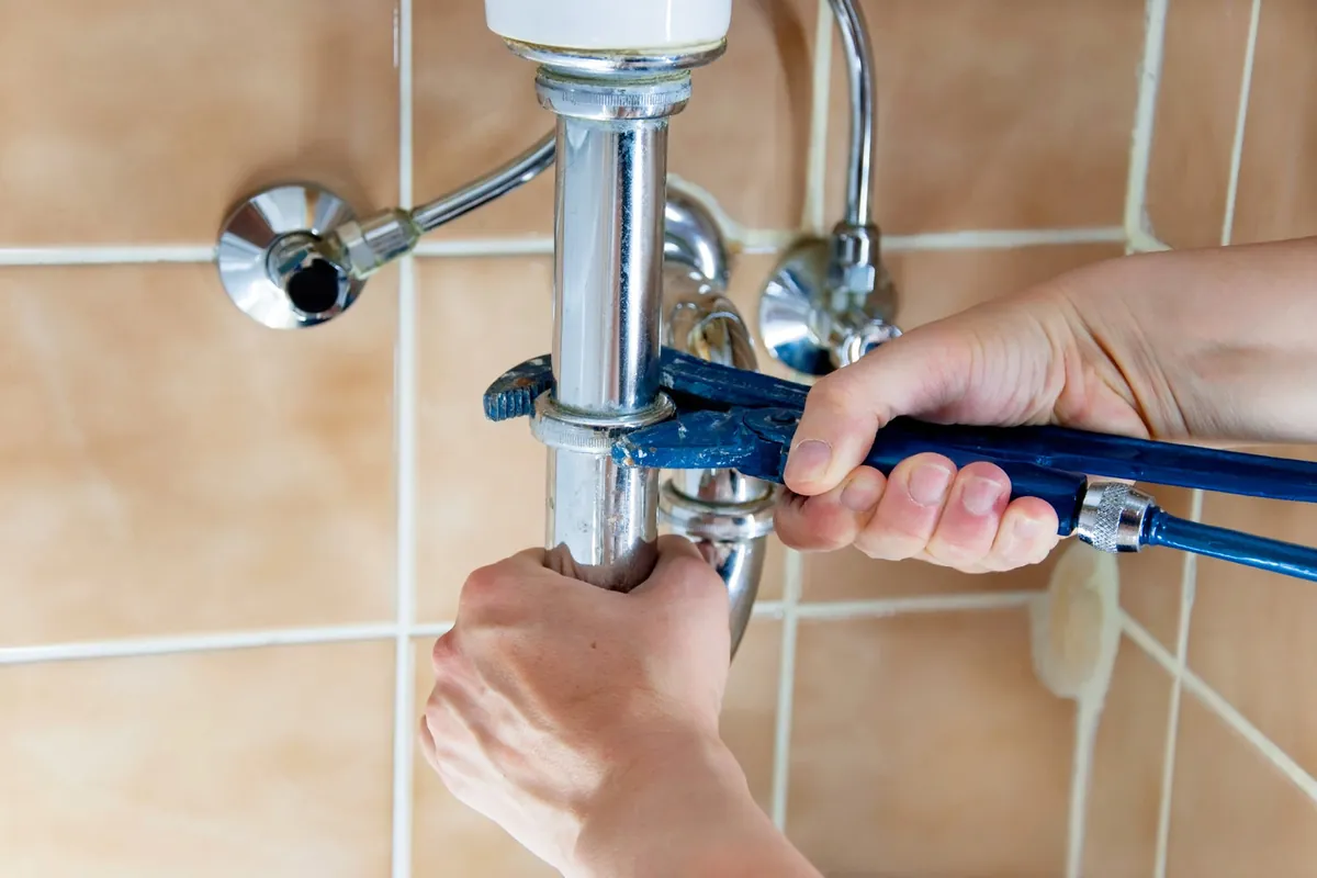 Plumber repairing a bathroom sink drain pipe